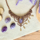 Handcrafted macramé necklace with an amethyst gemstone centerpiece and brass details, perfect as a gift from a small business for hippie, spiritual, and wellbeing-focused clients.